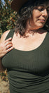 Woman wearing a green tank top outdoors with trees in the background